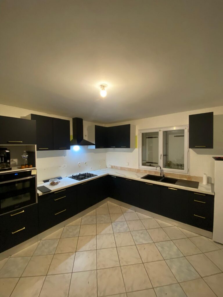 Cuisine d'angle noir mat avec plan de travail effet marbre installée à Bourg-en-Bresse