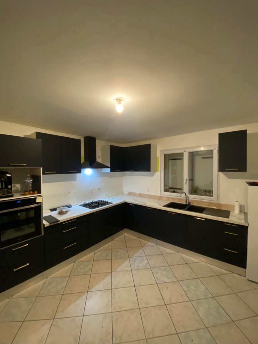 Cuisine d'angle noir mat avec plan de travail effet marbre installée à Bourg-en-Bresse