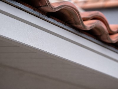 Gros plan sur un profilé de frisette ou cache-bandeaux en PVC blanc pour habillage de toit