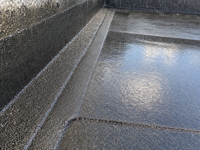 Gros plan sur une membrane d'étanchéité bitumineuse multicouche soudée sur support béton