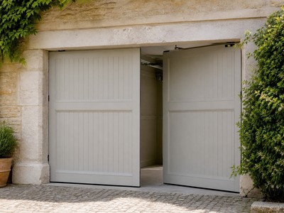 Porte de garage battante traditionnelle à deux vantaux entrouverte sur façade ancienne
