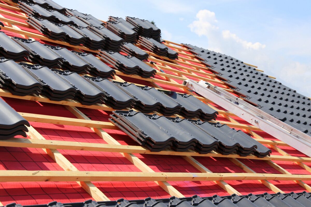 Chantier de rénovation de toiture : écran sous-toiture rouge, liteaux et tuiles anthracite prêtes à poser