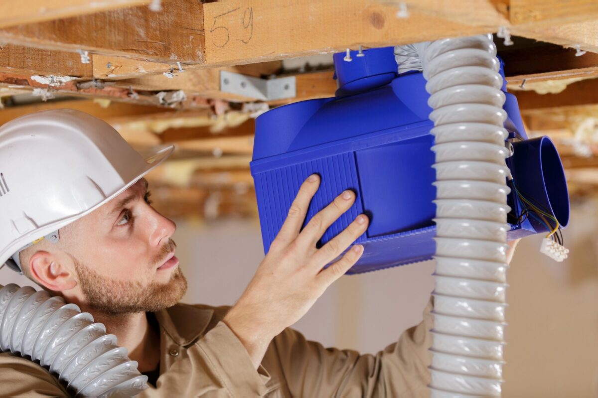 Artisan installant un groupe VMC simple flux dans les combles